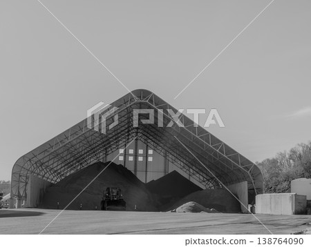 Large storage facility holds various materials in a covered structure in an industrial area during daytime Large storage facility holds various materials in a covered structure in an industrial area during daytime 138764090