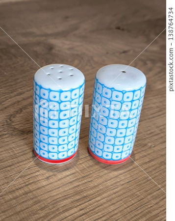 Ceramic salt and pepper shakers with blue pattern on the table 138764734