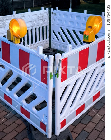 Plastic safety barriers with flashing yellow lights are installed in the pedestrian area.  138764735