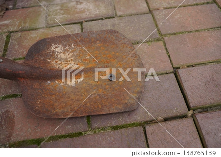 Rusty metal shovel blade lying on brick pavement Rusty metal shovel blade lying on brick pavement 138765139