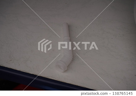 White plastic ribbed tube connector on a light surface, photographed from above 138765145