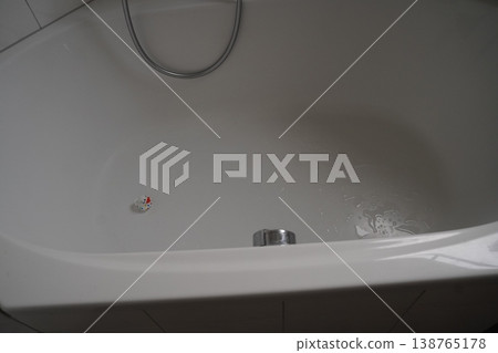 White bathroom sink with drain stopper, faucet hose, and a small colorful plug near the drain White bathroom sink with drain stopper, faucet hose, and a small colorful plug near the drain 138765178