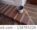 Small empty plastic flowerpot on brick step near door frame, with fallen dry leaf on patio 138765226