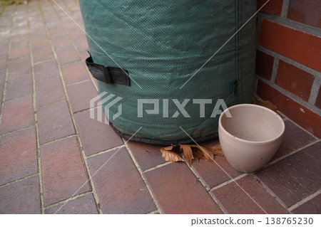 Green padded cylinder with strap on brick pavement beside a brick wall, with a ceramic bowl and dry leaves on the ground Green padded cylinder with strap on brick pavement beside a brick wall, with a ceramic bowl and dry leaves on the ground 138765230