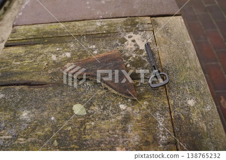 Rusty key and old metal tool on weathered wooden table with moss and stains Rusty key and old metal tool on weathered wooden table with moss and stains 138765232