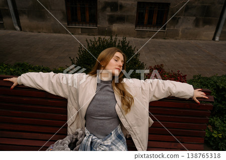 Woman sits on a bench in a park and enjoys the moment during the afternoon Woman sits on a bench in a park and enjoys the moment during the afternoon 138765318