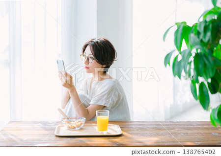 女人看著智能手機時吃早餐 138765402