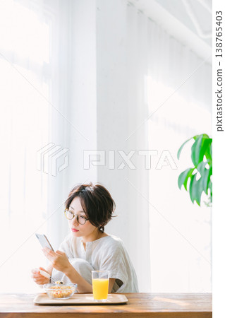 女人看著智能手機時吃早餐 138765403