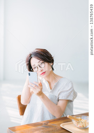 Woman eating breakfast while looking at smartphone Woman eating breakfast while looking at smartphone 138765439