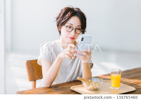 女人看著智能手機時吃早餐 138765460