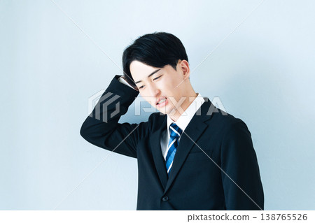 一個身穿西裝的年輕男子雙手抱頭。 138765526