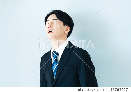 A young man in a suit holding his head in his hands. A young man in a suit holding his head in his hands. 138765527