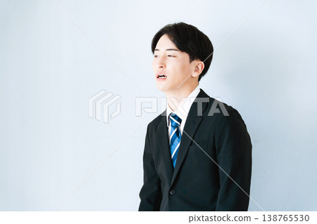 一個身穿西裝的年輕男子雙手抱頭。 138765530