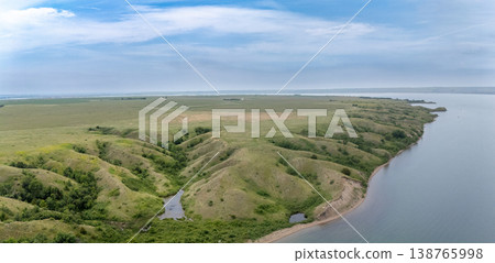 Expansive green hills and calm waters along the river under a cloudy sky near the countryside Expansive green hills and calm waters along the river under a cloudy sky near the countryside 138765998