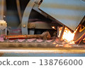 Sparks fly from a grinding machine while shaping metal on a workshop bench 138766000