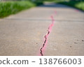 Cracked concrete surface with pink chalk markings in outdoor setting during daytime 138766003