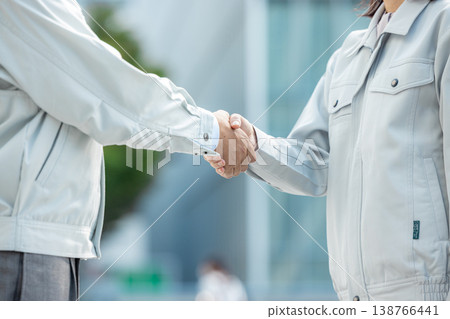 畫面中,一男一女身穿工作服,正在握手。 畫面中,一男一女身穿工作服,正在握手。 138766441