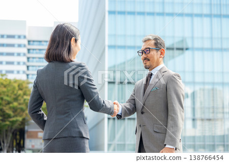 Men and women in suits shake hands 138766454