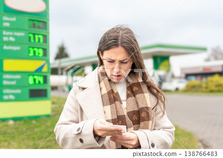 Budget stress young woman calculating petrol costs Budget stress young woman calculating petrol costs 138766483