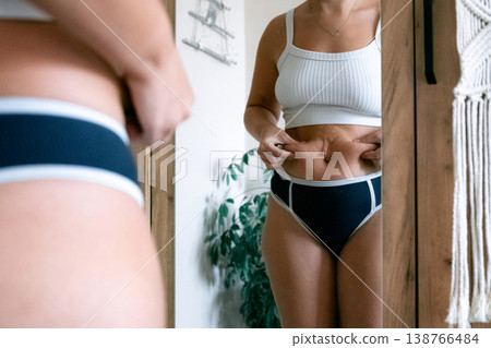 Woman at home. Touching stomach near mirror. Mental health conce Woman at home. Touching stomach near mirror. Mental health conce 138766484