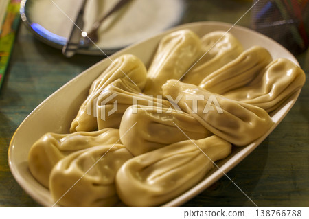 Georgian khinkali juicy meat dumplings on a ceramic plate in a restaurant. High quality photo Georgian khinkali juicy meat dumplings on a ceramic plate in a restaurant. High quality photo 138766788