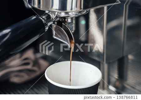 Fresh Espresso Flowing from Portafilter into Takeaway Paper Cup. High quality photo Fresh Espresso Flowing from Portafilter into Takeaway Paper Cup. High quality photo 138766811