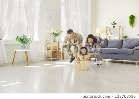 Family playing at home, parents push daughter riding pretend car in basket 138768596