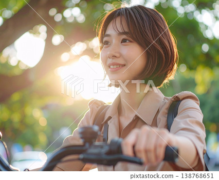 一位微笑的年輕女子騎著腳踏車上班，陽光透過樹梢灑下斑駁的光影。 138768651