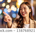 夜晚的城市裡，一位年輕女子麵帶微笑，指著前方。 138768921
