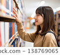 一名女學生在圖書館書架上尋找書籍。 138769065