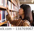 一名女學生在圖書館書架上尋找書籍。 138769067