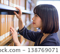 一名女學生在圖書館書架上尋找書籍。 138769071