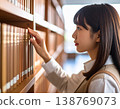 一名女學生在圖書館書架上尋找書籍。 138769073