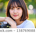 一位留著清爽波波頭的年輕女子在公園裡騎著腳踏車，笑容燦爛。 138769088