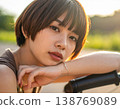 一位留著清爽波波頭的年輕女子在公園裡騎著腳踏車，笑容燦爛。 138769089