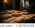Making bread in bakery. Uncooked bread dough on a rack ready for baking in oven. Prepared raw bread dough shaped into loaves on shelf. Racks of uncooked pastry dough. Food industry. 138769198