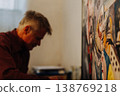 Old man artist painting oils in his studio. 138769218
