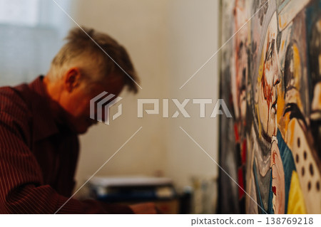 Old man artist painting oils in his studio. 138769218