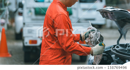 A male auto mechanic checks the engine oil level gauge. 138769496