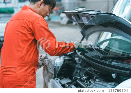 汽車修理工拔出機油尺檢查機油油位。 汽車修理工拔出機油尺檢查機油油位。 138769504