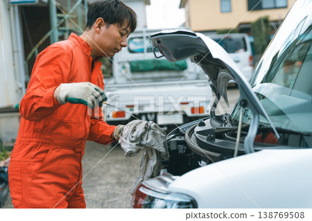 打開汽車引擎蓋，取下機油油位計，用抹布擦掉黏貼在上面的機油。 138769508