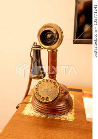 A vintage telephone with an elegantly curved receiver and a beautiful golden dial. A vintage telephone with an elegantly curved receiver and a beautiful golden dial. 138771241