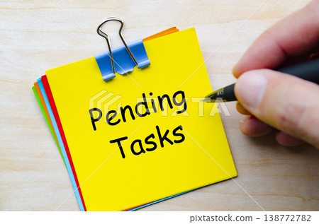 Pending tasks written on yellow sticky note representing unfinished work and task management. Pending tasks written on yellow sticky note representing unfinished work and task management. 138772782