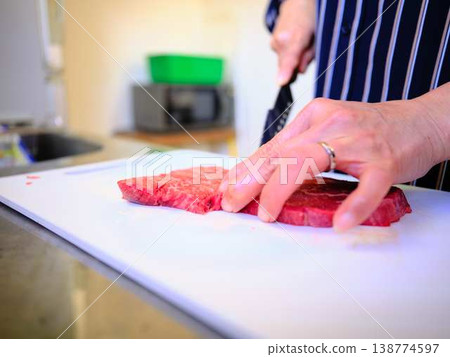 一位女廚師正在切割國產日本黑毛牛腿肉 一位女廚師正在切割國產日本黑毛牛腿肉 138774597
