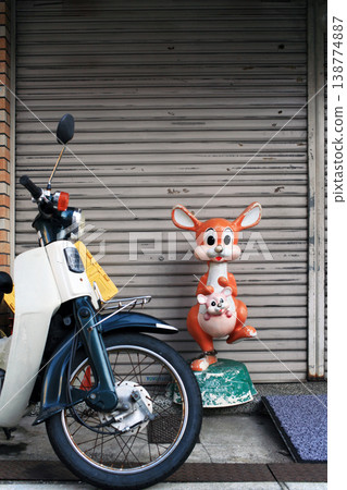 The mascot and motorcycle in front of the store 138774887