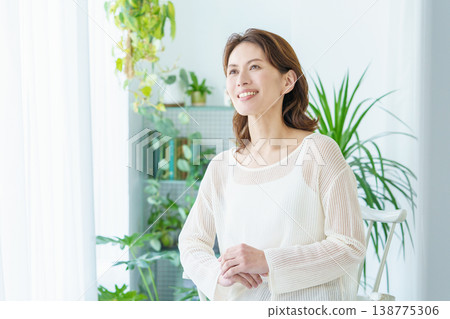 A portrait of a middle-aged woman standing by a window. 138775306