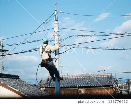 Electrical work on a utility pole in a residential area. Electrical work on a utility pole in a residential area. 138776412