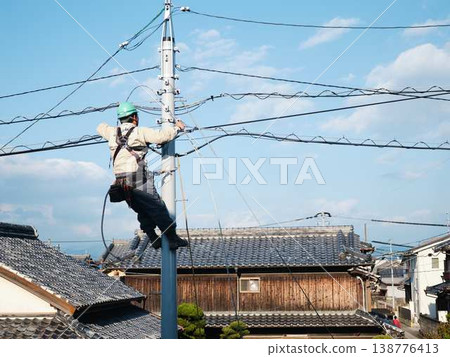 Electrical work on a utility pole in a residential area. Electrical work on a utility pole in a residential area. 138776413