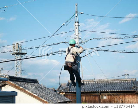 Electrical work on a utility pole in a residential area. Electrical work on a utility pole in a residential area. 138776414