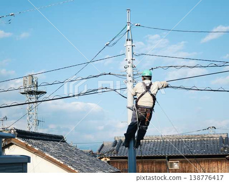 Electrical work on a utility pole in a residential area. 138776417